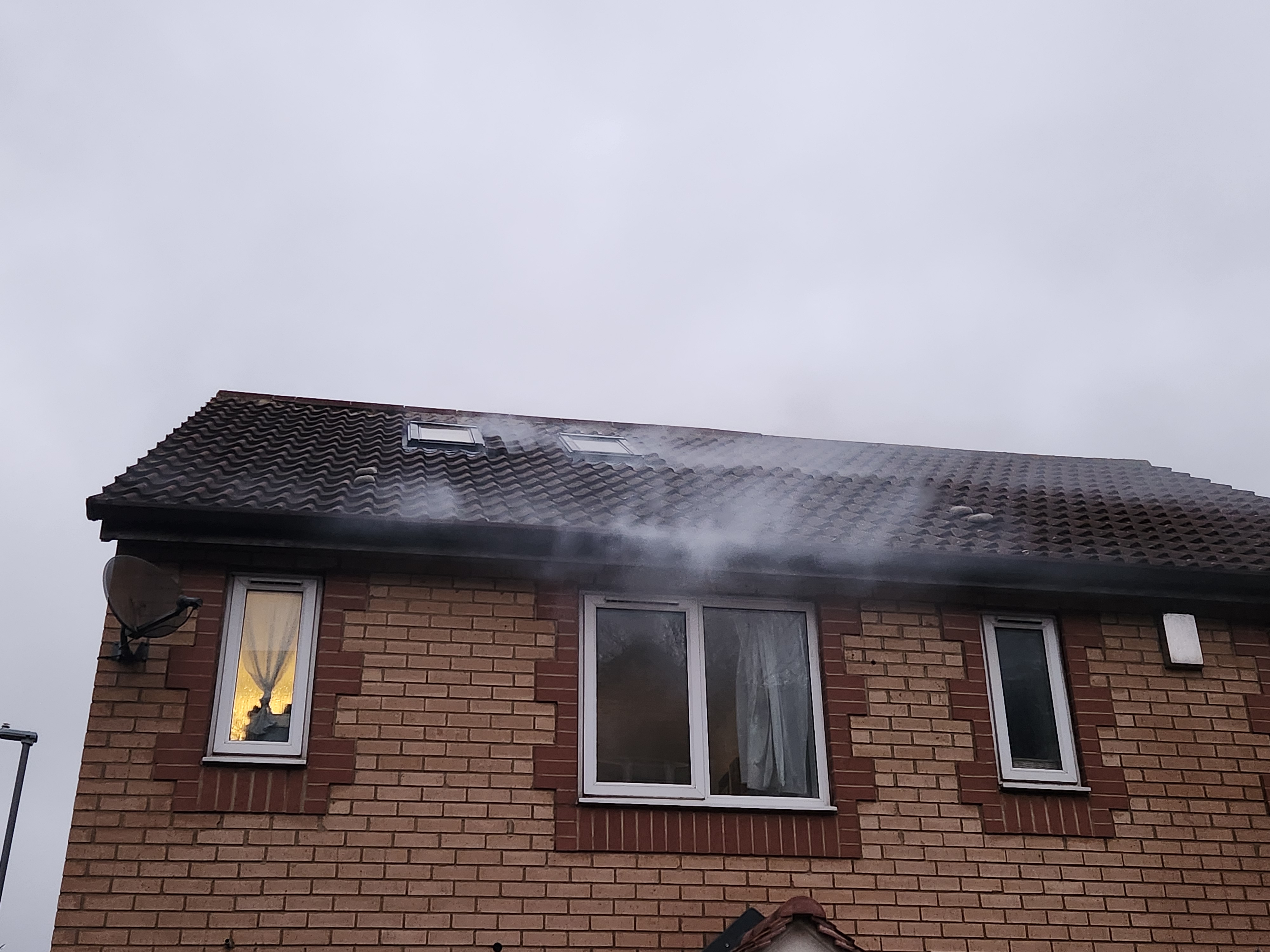 Smoke tracing during a blower door test — smoke escaping at the eaves of the roof, visualising the air-leakage path between the roof structure and external wall