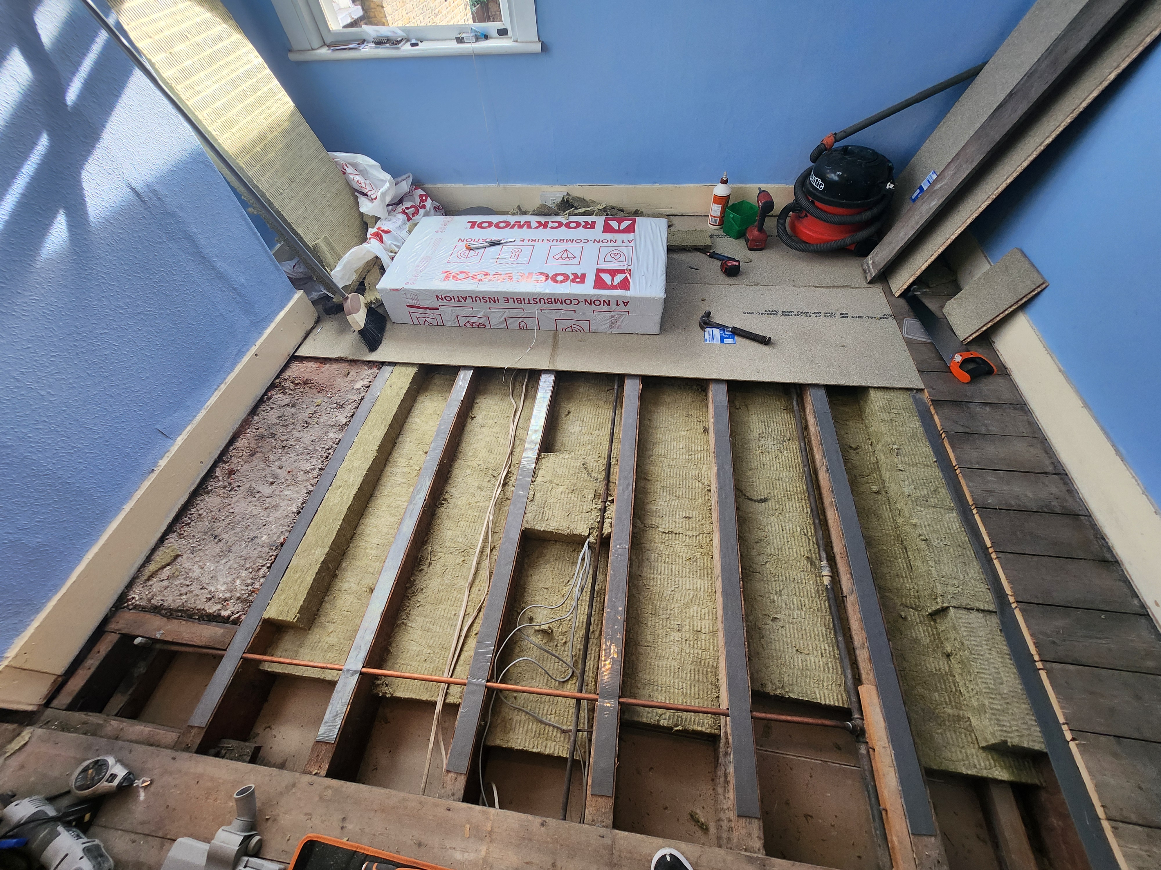 N17 project · acoustic floor build-up mid-installation — Rockwool packs ready to be cut to joist centres, resilient bars and new boards being fixed