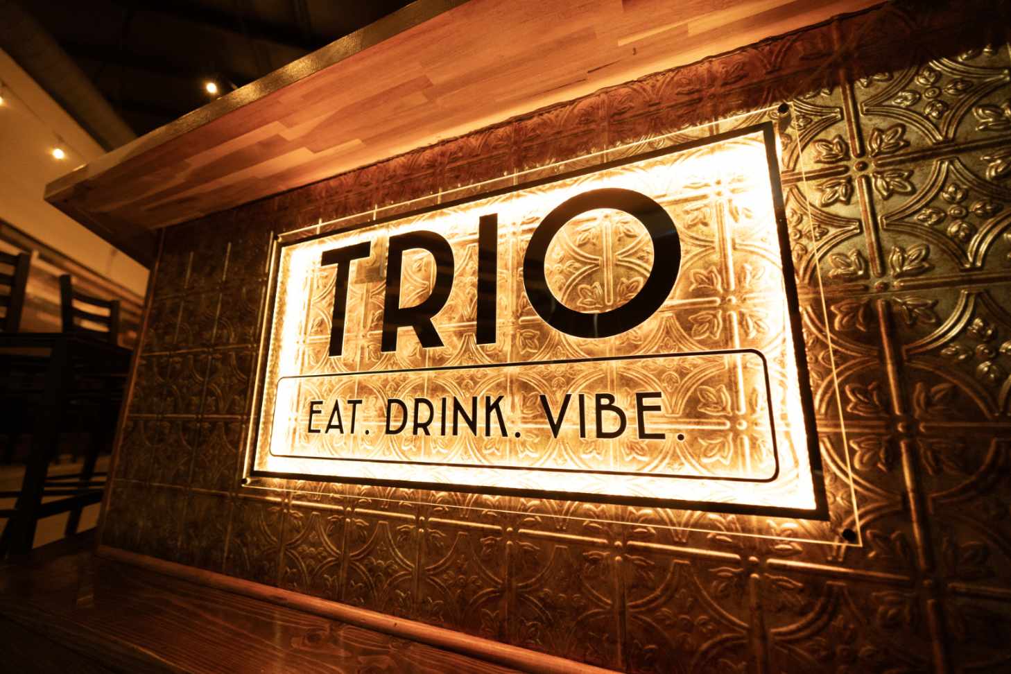 Backlit Trio sign on copper tin wall