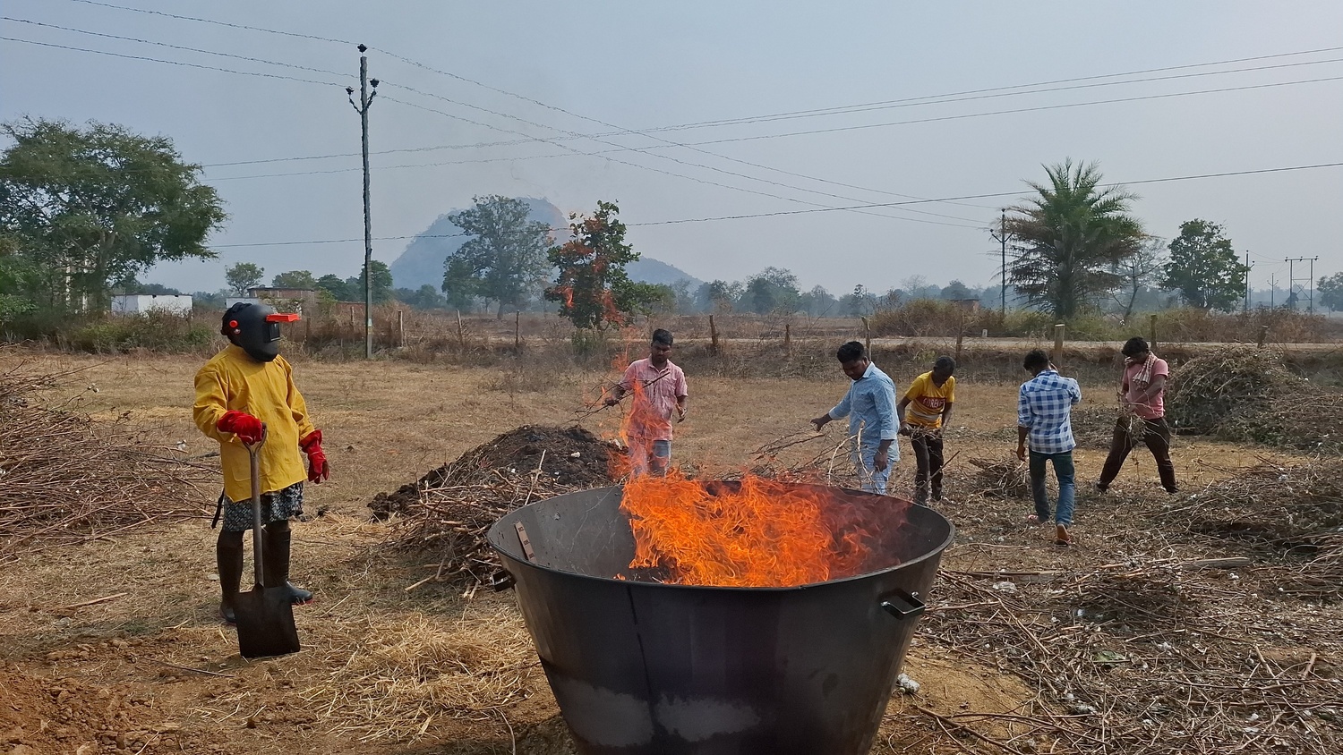 Farmer-owners tending a flaming biochar kiln, coastal Odisha
