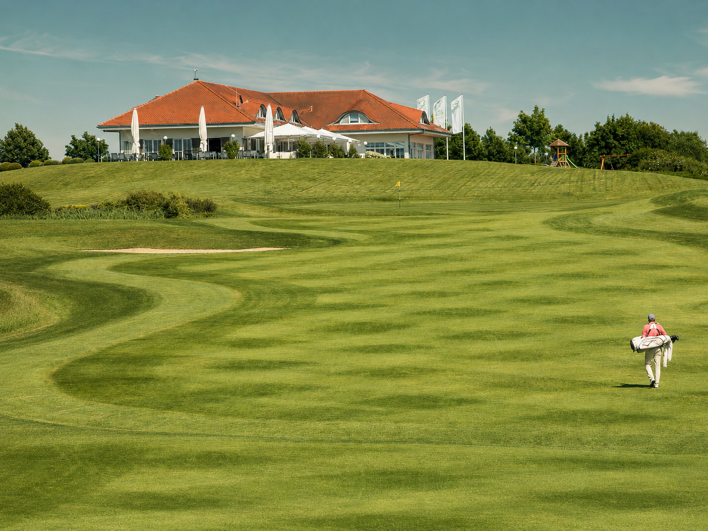 Golfer auf dem Fairway mit Clubhaus im Hintergrund