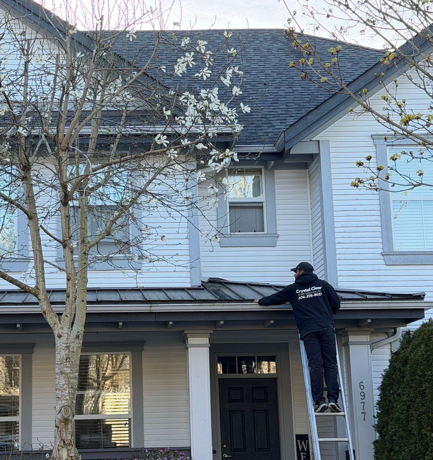 Crystal Clear Home Services LTD worker on ladder cleaning gutters