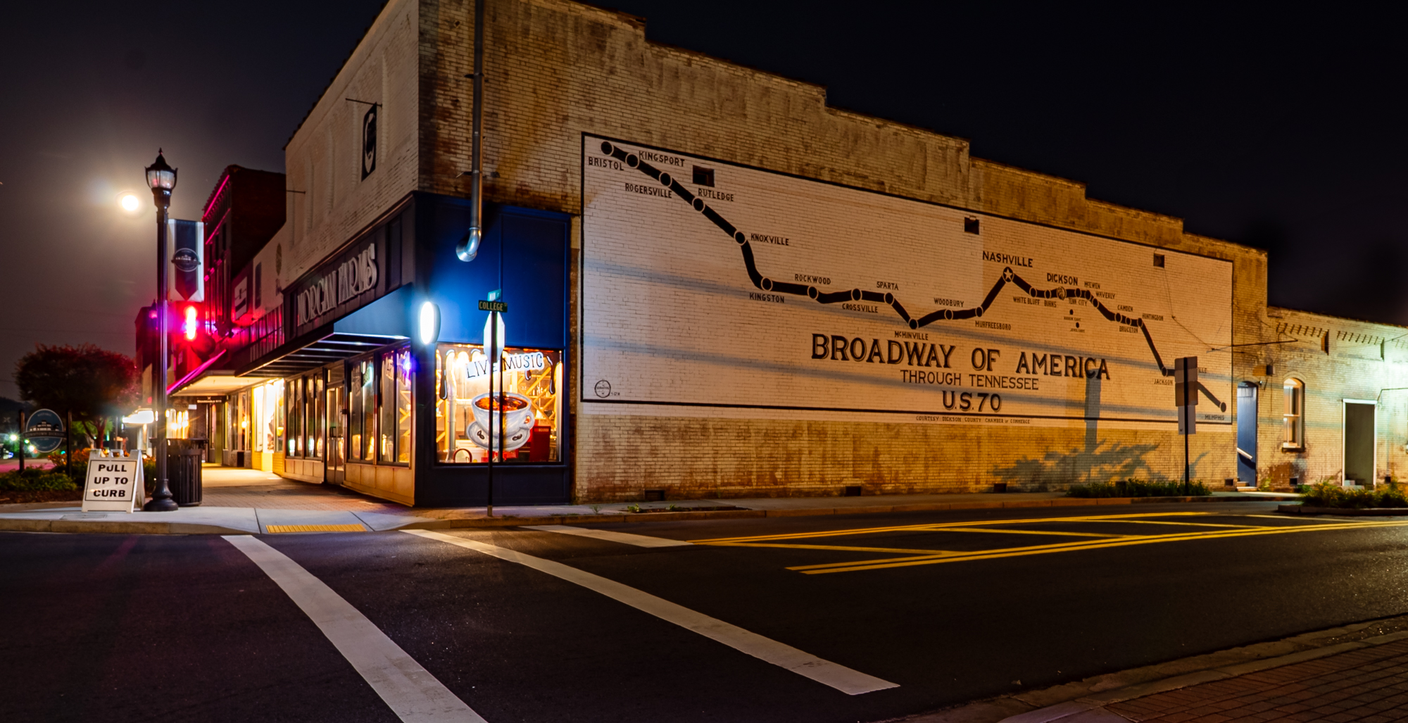 Color photograph of the Broadway of America mural and downtown storefronts at night