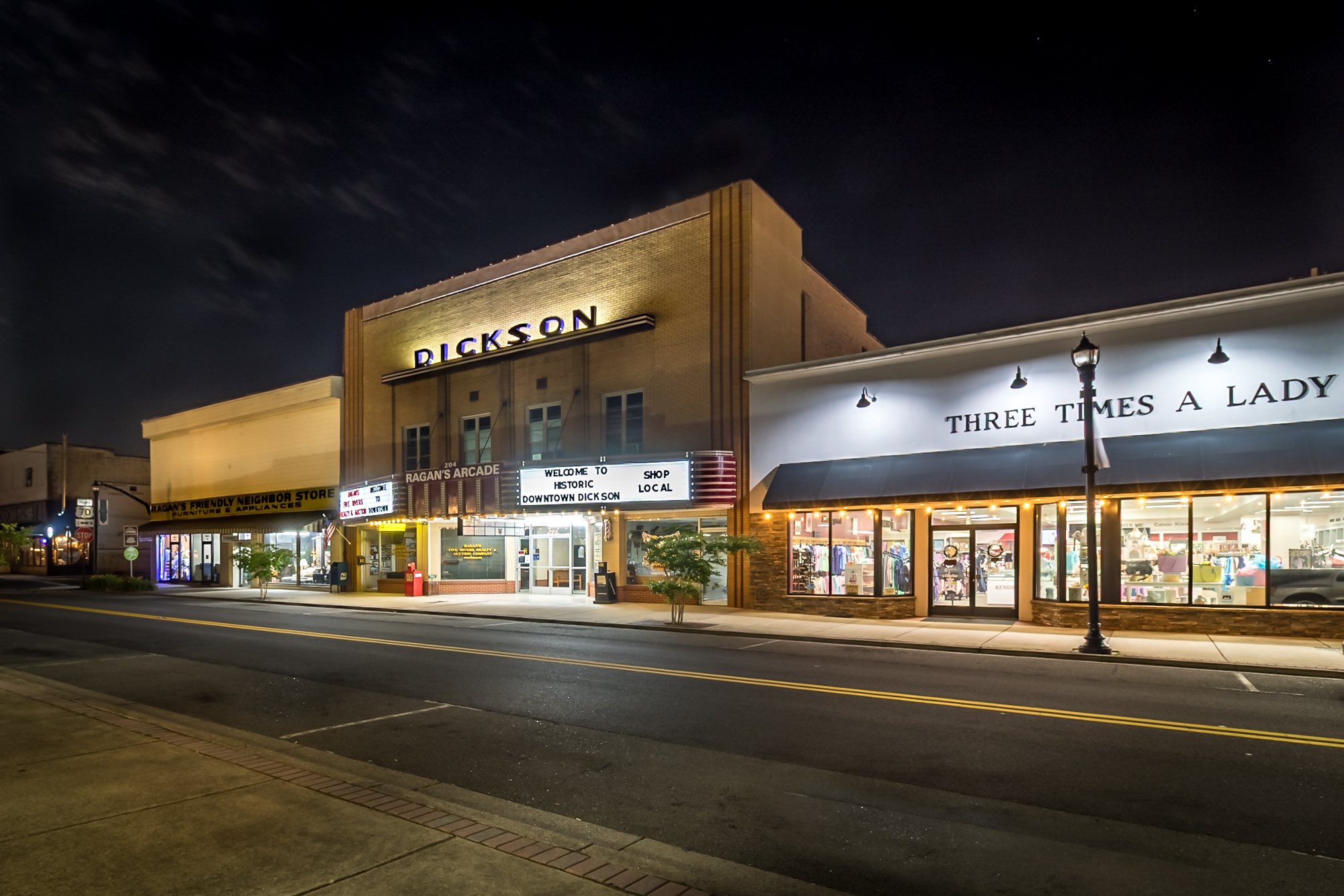 Color photograph of the historic Dickson Theater building and adjacent downtown storefronts at night