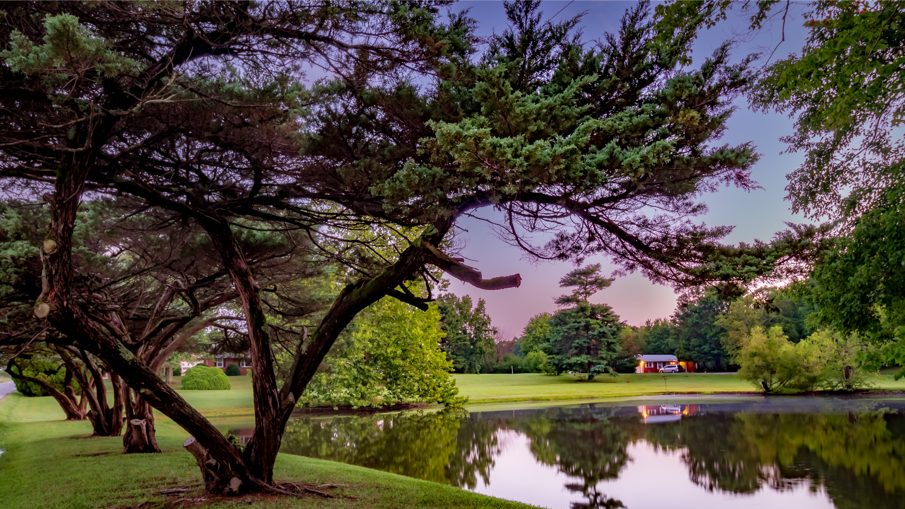 Color photograph of a glowing sunset reflected across a calm lake