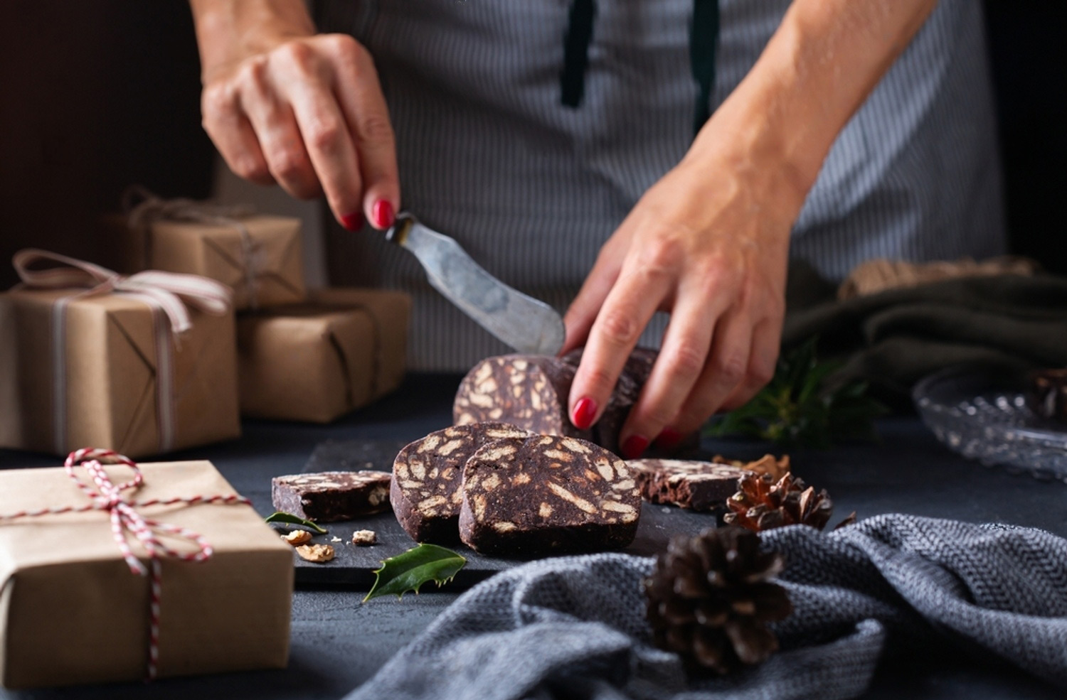 Hands slicing Not A Salami beside hand-wrapped gift boxes