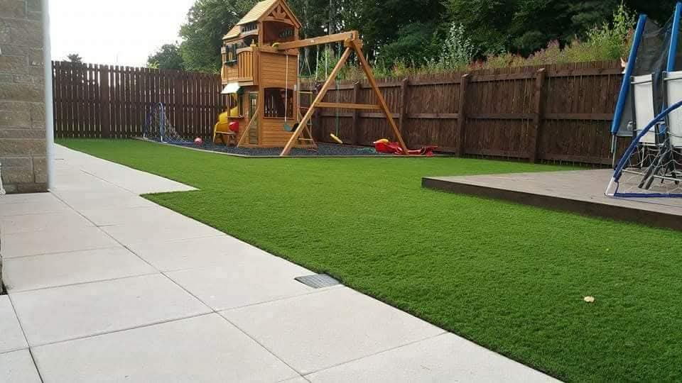 Family garden with stone path, vibrant artificial lawn and playhouse